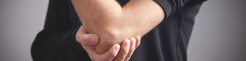 Tennisarm Persoon houdt de elleboog vast als teken van elleboogklachten of een tennisarm
