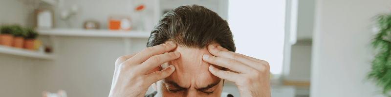 Migraine laten behandelen Persoon houdt het hoofd vast als teken van migraine