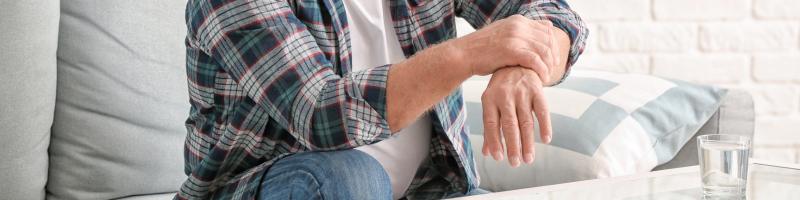 Parkinson Persoon die de pols vasthoudt