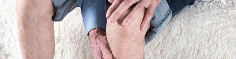 Fysiotherapie bij Artrose Persoon die de knie vasthoudt als teken van knieklachten als gevolg van artrose