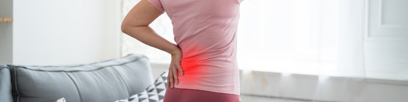 Hernia onderrug behandelen bij Rugcentrum Parkstad Persoon die de onderrug vasthoudt, met een visuele aanduiding van pijnklachten in de onderrug als gevolg van een hernia